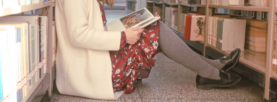 床に座りこんで本を読む女性
