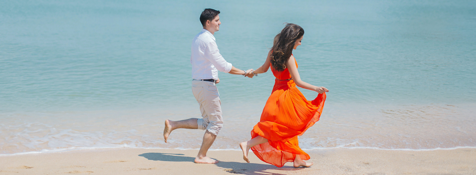 手を繋いで海辺を歩くカップル